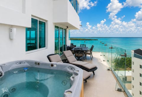 #323 - Penthouse Combo - 8 bedrooms, 6 baths sleeps 18 Glass railing outlines the balcony with cushioned loungers, a spa tub, and an iron dining set overlooking turquoise water.