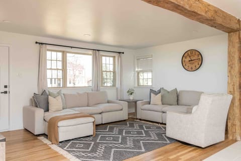 Bright living room w/ plush sectional, patterned rug & large windows bringing in natural light