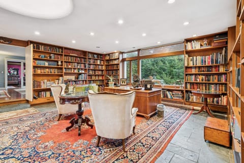 The heart of the home—our iconic library with soaring windows and walls of books, perfect for quiet moments or cozy connection. Take a look around!