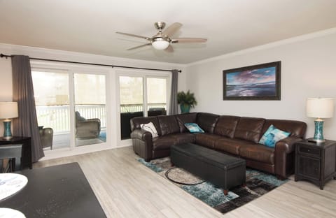 Relax in your spacious living room with plush leather seating and balcony access for morning coffee or evening unwinding.