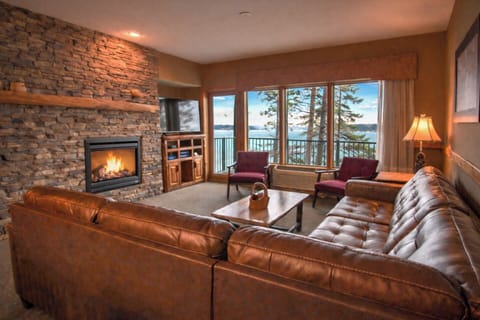 Cozy waterfront living room with stone fireplace and panoramic views