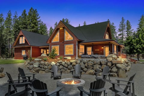 Backside of the house with hot tub and fireplace facing the forest.