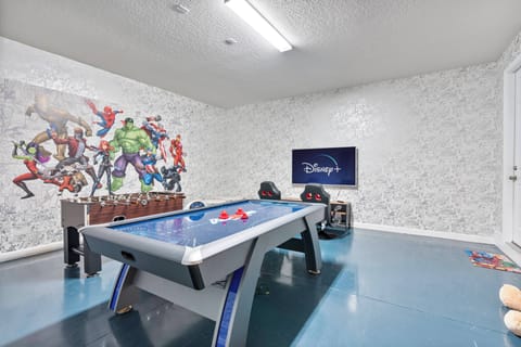 Enter our lively game room featuring a vibrant superhero mural and sleek blue flooring. Enjoy friendly matches on the air hockey table and unwind in the cozy seating, perfect for relaxing between games.