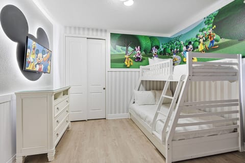 Bright and playful, this children's room features a fun bunk bed and a whimsical mural showcasing beloved characters. The light wood flooring and white furniture create a cheerful atmosphere, perfect for imaginative adventures.