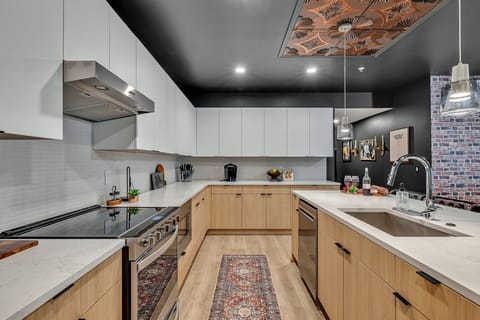 The fully equipped modern kitchen features culinary essentials, stainless steel appliances, and island bar seating.