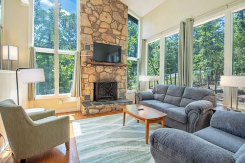 Living area includes fireplace, television, lounge seating, and expansive windows