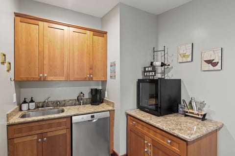 Kitchen (second floor)- This compact and efficient kitchenette features sleek wooden cabinetry and granite countertops, complemented by modern appliances. Ideal for quick meals or evening drinks, it's a convenient addition to any home space.
