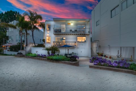 A stunning view of the property during twilight with vibrant skies and the beach just steps away, creating a picturesque and inviting scene.