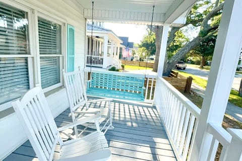 Picturesque classic front porch with rocking chairs and swing chair.