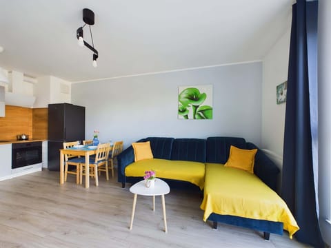 Cosy living room with an elegant, dark blue corner sofa and small coffee table ideal for those, who want to drink a morning coffee in a pleasant atmosphere.