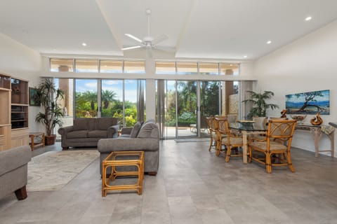 Relax in your bright, spacious living area with soaring ceilings and floor-to-ceiling windows framing lush garden views. Thoughtfully designed with coastal-inspired décor and comfortable seating, this open space invites you to unwind.
