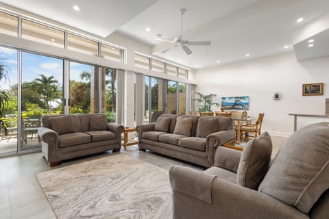 Sink into plush comfort in this airy living room, where sunlight streams through floor-to-ceiling windows revealing lush tropical views. Perfect for unwinding after your adventures.