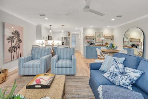 Living room with blue sofas, coastal decor, and kitchen view