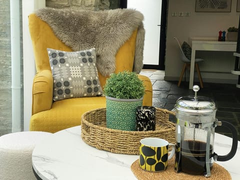 Conservatory bright yellow chair with cushion and throw and coffee table
