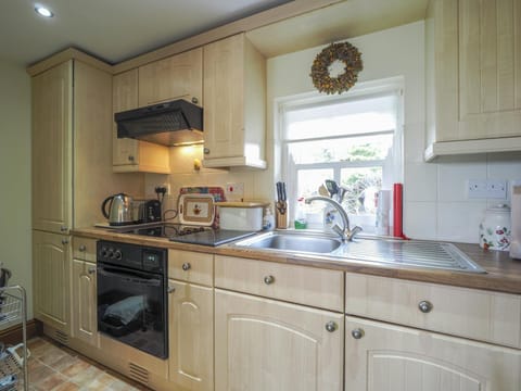 Fitted kitchen with oven and hob, kettle and toaster. Window overlooking the garden