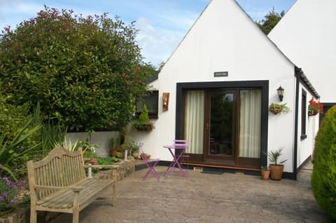 Patio with picnic bench, small table and two chairs outside Carni Lodge