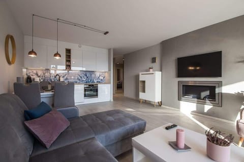 A cozy living room with a sectional sofa, TV on the wall, and warm lighting creating a relaxing ambiance.

