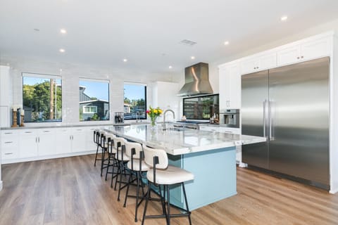 Feast in style with spacious seating, an island bar, white cabinetry, and a massive two-door refrigerator.