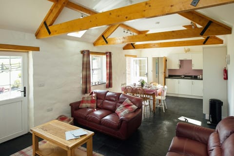 Open plan living room with leather sofas, coffee table, dining table, six chairs and kitchen area
