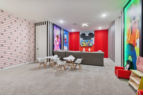 Step into a vibrant playroom featuring playful wallpaper and colorful artwork that sparks joy. The cozy carpet and modern furniture create a welcoming atmosphere, perfect for family fun or relaxation after a day of adventure.