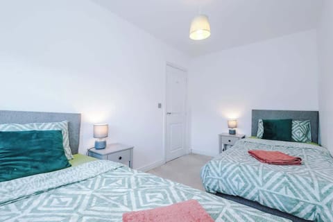 A bright twin bedroom featuring two comfortable single beds with soft bedding and fresh décor.