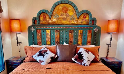 King-size bed with vibrant textiles and artistic accents.