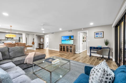 Modern living: Open concept living & dining area with large windows for ample natural light, and views for the golf course. The living room features a full-sized sleeper sofa, personal desk, and smart streaming TV with cable.