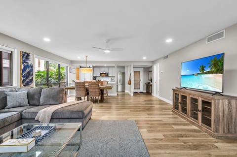 Modern living: Open concept living & dining area with large windows for ample natural light, and views for the golf course. The living room features a full-sized sleeper sofa, personal desk, and smart streaming TV with cable.