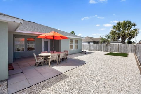 Spacious backyard with dining patio under bright orange umbrella, perfect for your morning coffee or evening meals.