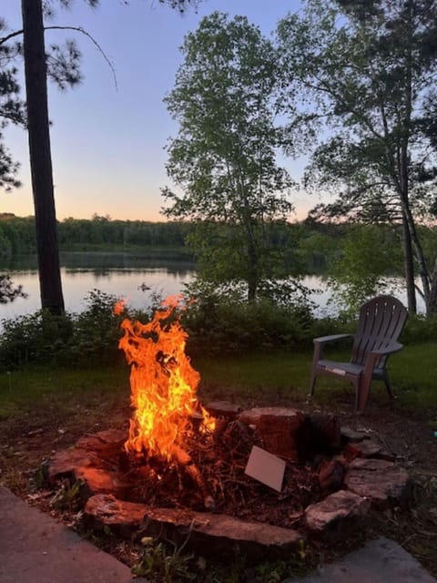 Lakeside fire pit area featuring a single wooden chair.