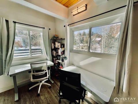 The workspace features two electronic adjustable standing desks with Ethernet hookups, providing a flexible and high-tech environment for productivity.