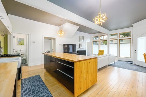 Kitchen opens to living room with bar seating, large TV, half bathroom