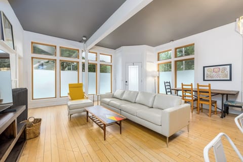 Beautiful sun lit living room with floor to ceiling windows, lots of seating!