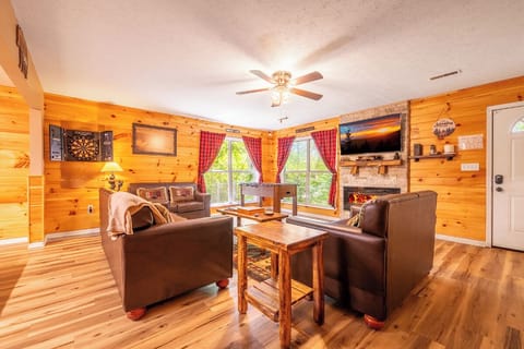 Settle into this cozy living room with warm wood walls, plush leather seating, and a rustic fireplace—your perfect retreat after a day of exploring.