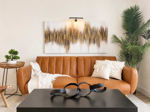 Spacious living room featuring a cozy sofa, two stylish armchairs, a full-size air mattress, and a 65" Smart TV with preloaded access to Netflix, Hulu, and Disney+, all set up for your enjoyment.