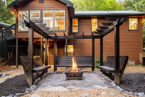Cozy cabin with pergola seating, firepit, and wooded views—perfect for relaxing!