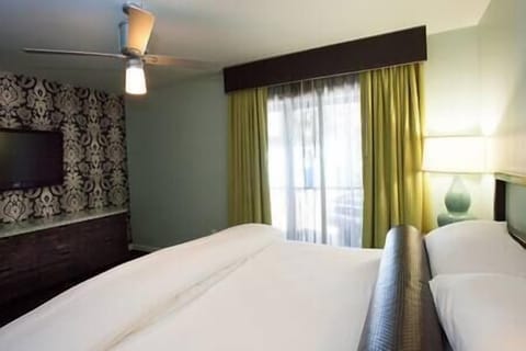 Bedroom includes flat screen TV, dresser, night stand, and access to patio