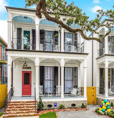 The front view of one of our two 5-bedroom, 5-bath homes on world-famous Canal Street, featuring the iconic "MARDI GRAS BEAD DOG" statue, offers a captivating scene with streetcars passing by.