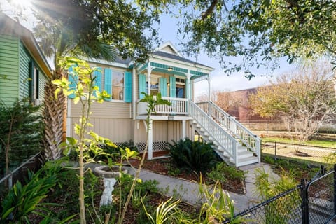 Bright coastal cottage with turquoise trim and lush landscaping.