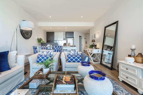 LIVING AREA: Sunlight fills the space through floor-to-ceiling windows, offering sweeping views of the Docklands waterfront. With plush seating and a calm, open feel, it’s the perfect spot for slow mornings, quiet reads, or laid-back evenings.