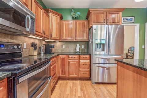 Modern kitchen with stainless steel appliances, granite countertops, and rich wood cabinets.