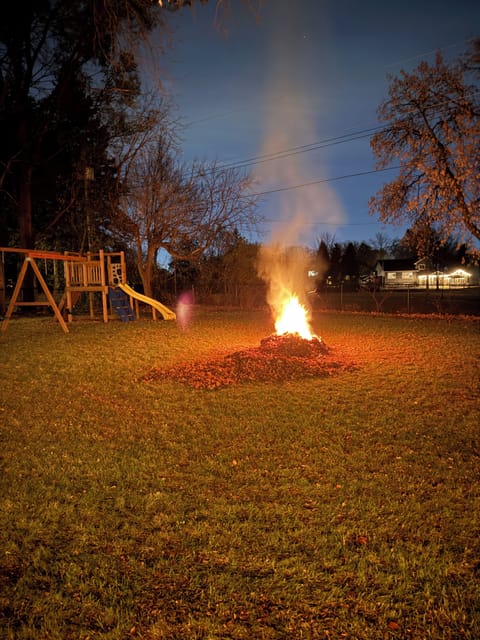 Backyard has fire pit, deck, grill and play set for kids. 
