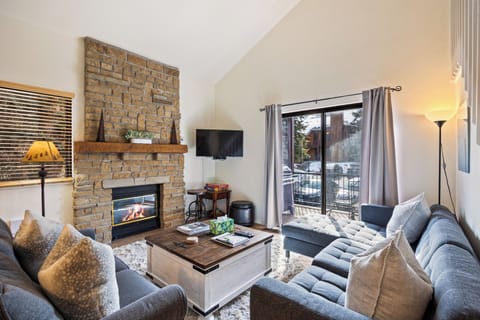 Bright and inviting living room featuring a comfortable sectional, fireplace, and sliding doors that open to the outdoor patio. Perfect for relaxing after a day of adventure.