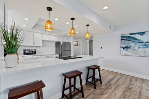 Spacious eat in kitchen area with bar seating, modern lighting, and a bright open layout for gathering.