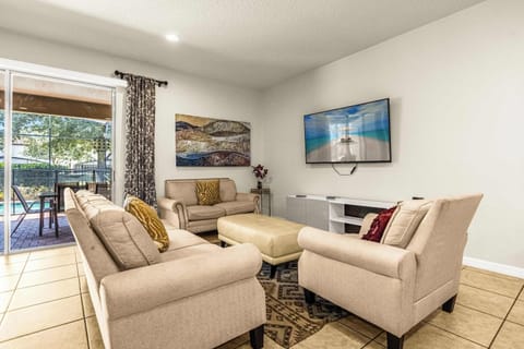 Private living room with plush cream seating, a large TV, and sliding doors opening to the poolside patio.
