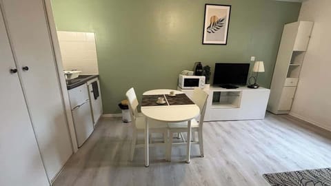 Coin repas pour deux personnes séparant la cuisine du salon.
Salon avec canapé convertible et télévision.
Espace de cuisine équipée avec petit réfrigérateur, micro-ondes, machine à café et plaques de cuisson.