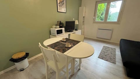 Coin repas pour deux personnes séparant la cuisine du salon.
Salon avec canapé convertible et télévision.
Espace de cuisine équipée avec petit réfrigérateur, micro-ondes, machine à café et plaques de cuisson.