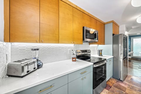 Showcasing the electric range and stainless-steel fridge, this sleek kitchen balances high function with effortless coastal style.
