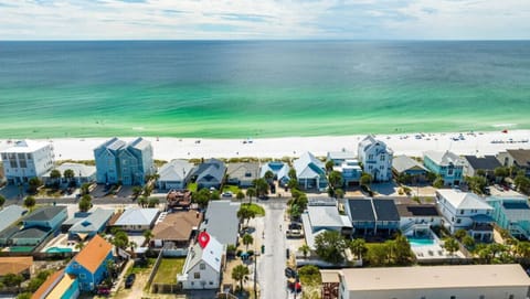 Aerial view of beachfront vacation rental community with emerald waters and white sand beach nearby.