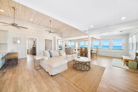 Sink into plush sofas while ocean waves fill your view through expansive windows in this airy, coastal-inspired living space.